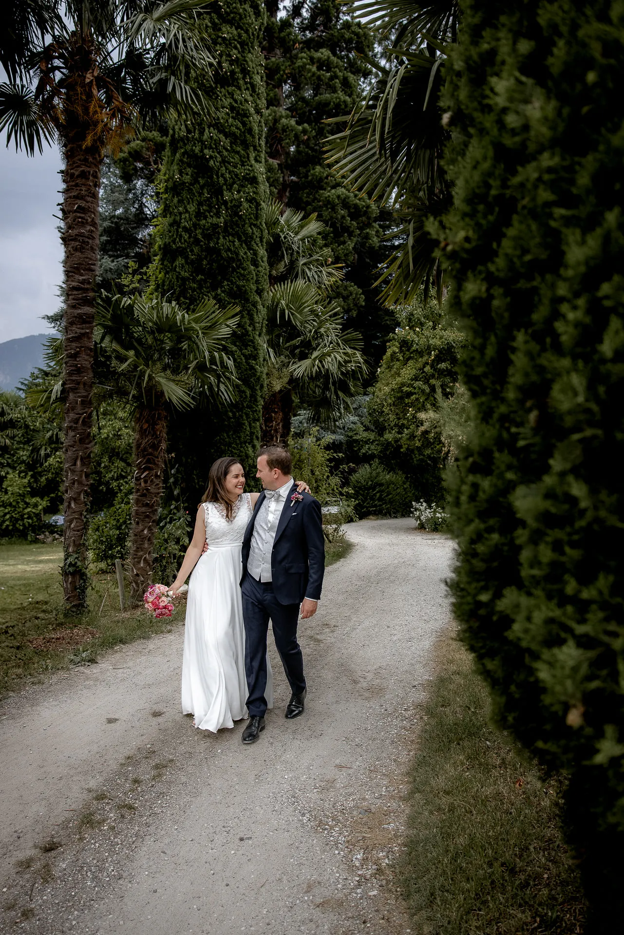 Brautpaar Ann-Kathrin und Tobias spaziert durch Palmengarten bei Italien-Hochzeit in Castel Pienzenau