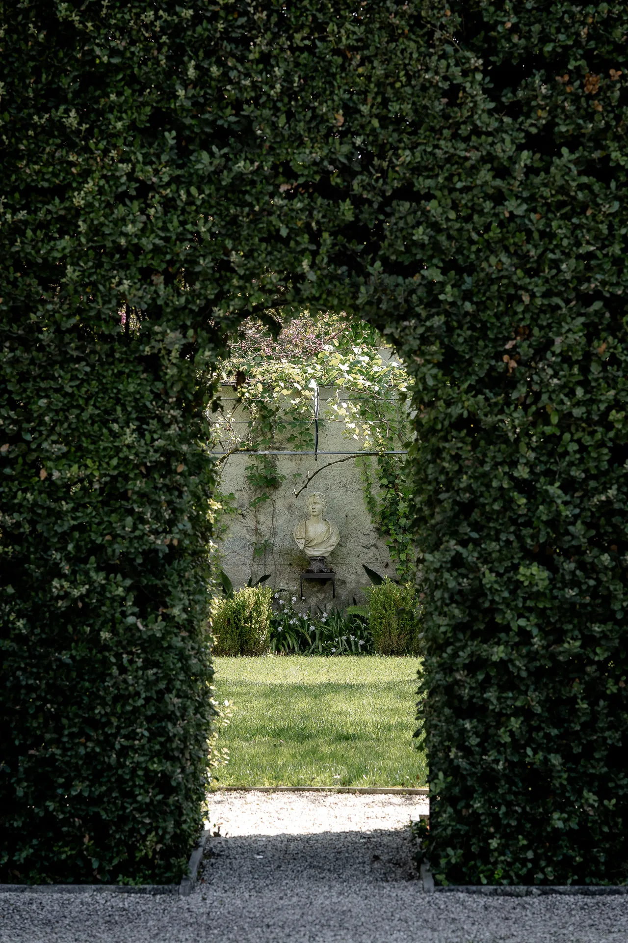 Romantischer Durchblick durch Hecke zum antiken Brunnen in Garten Villa Balbiano