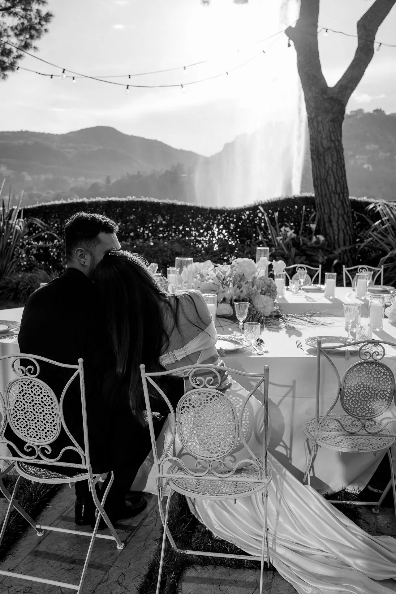 Intimer Brautpaar-Moment an Hochzeitstafel mit Bergpanorama Schwarz-Weiß