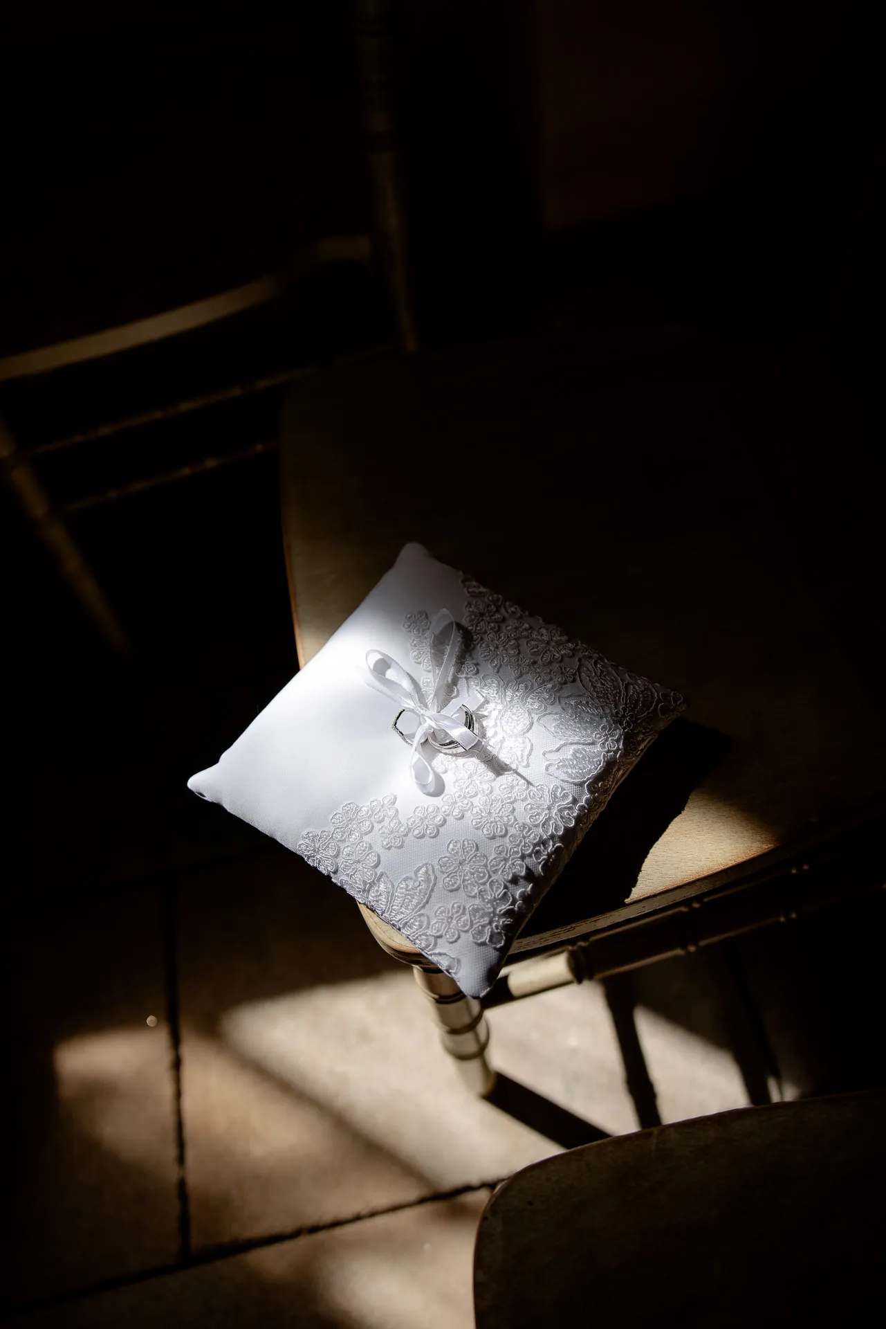 Elegantes Ringkissen mit Spitze und Satinband im dramatischen Lichteinfall