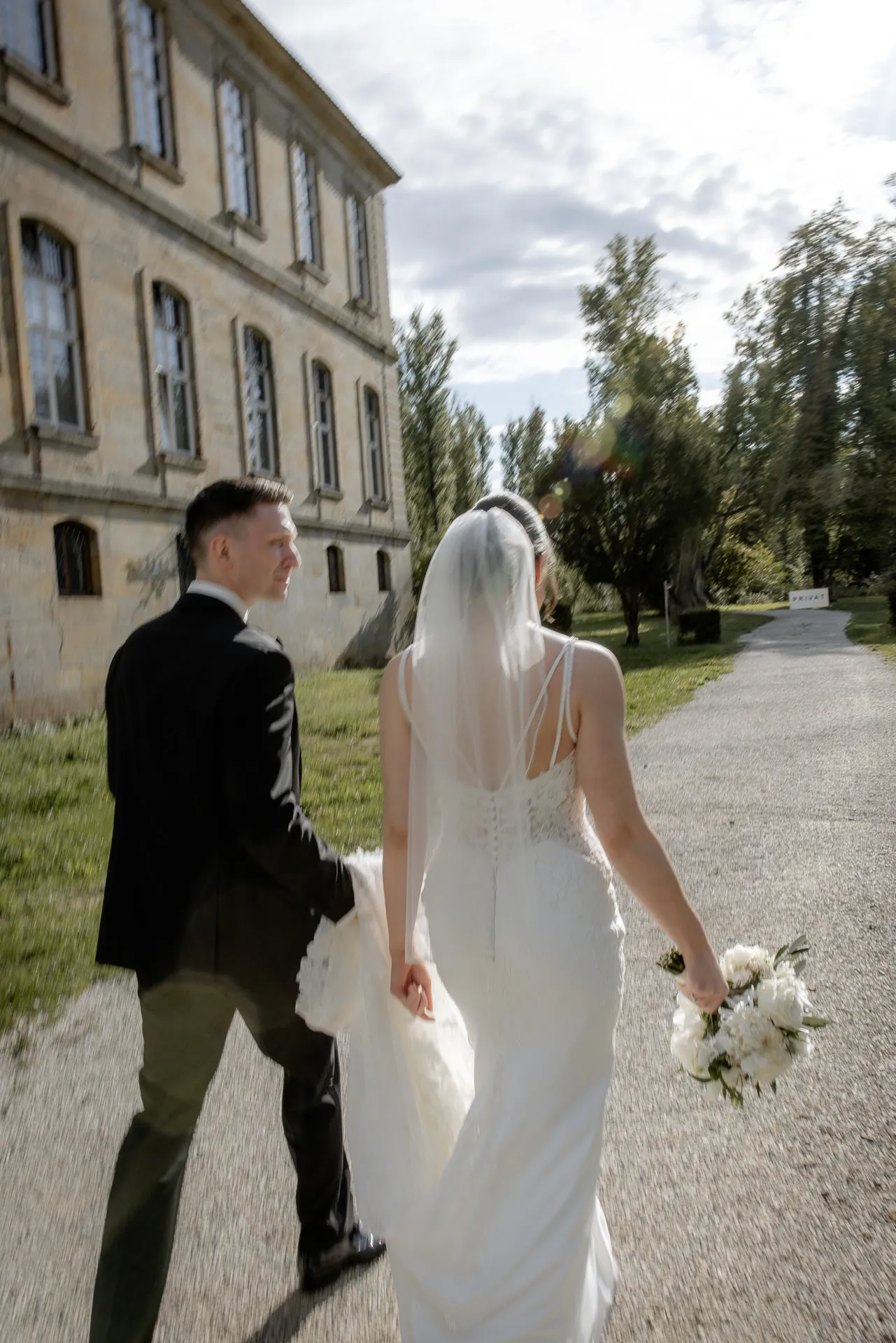 Brautpaar spaziert durch Schlossanlage Eyrichshof mit Schleier und Brautstrauß