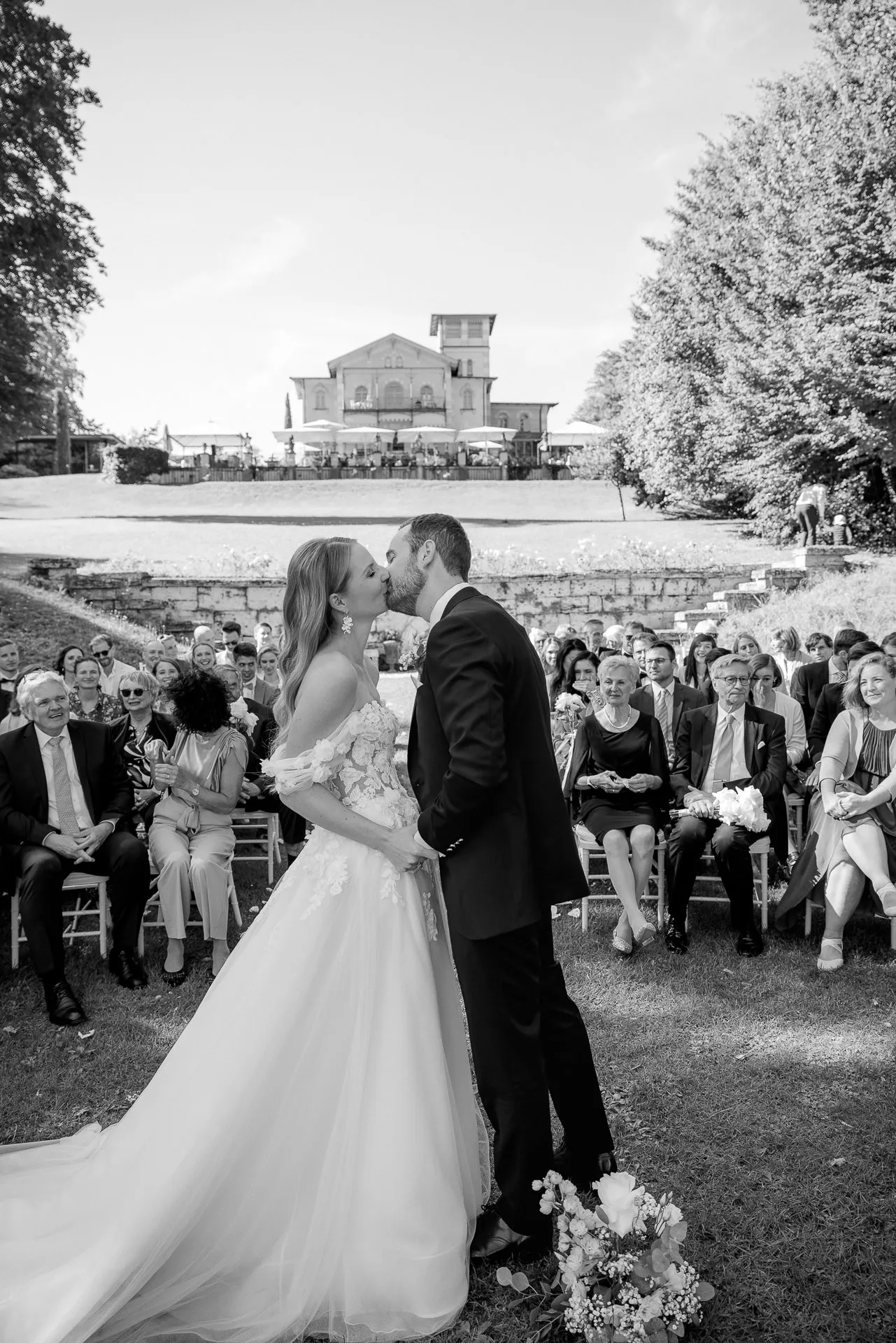 Küssendes Brautpaar bei Trauung mit La Villa und Gästen