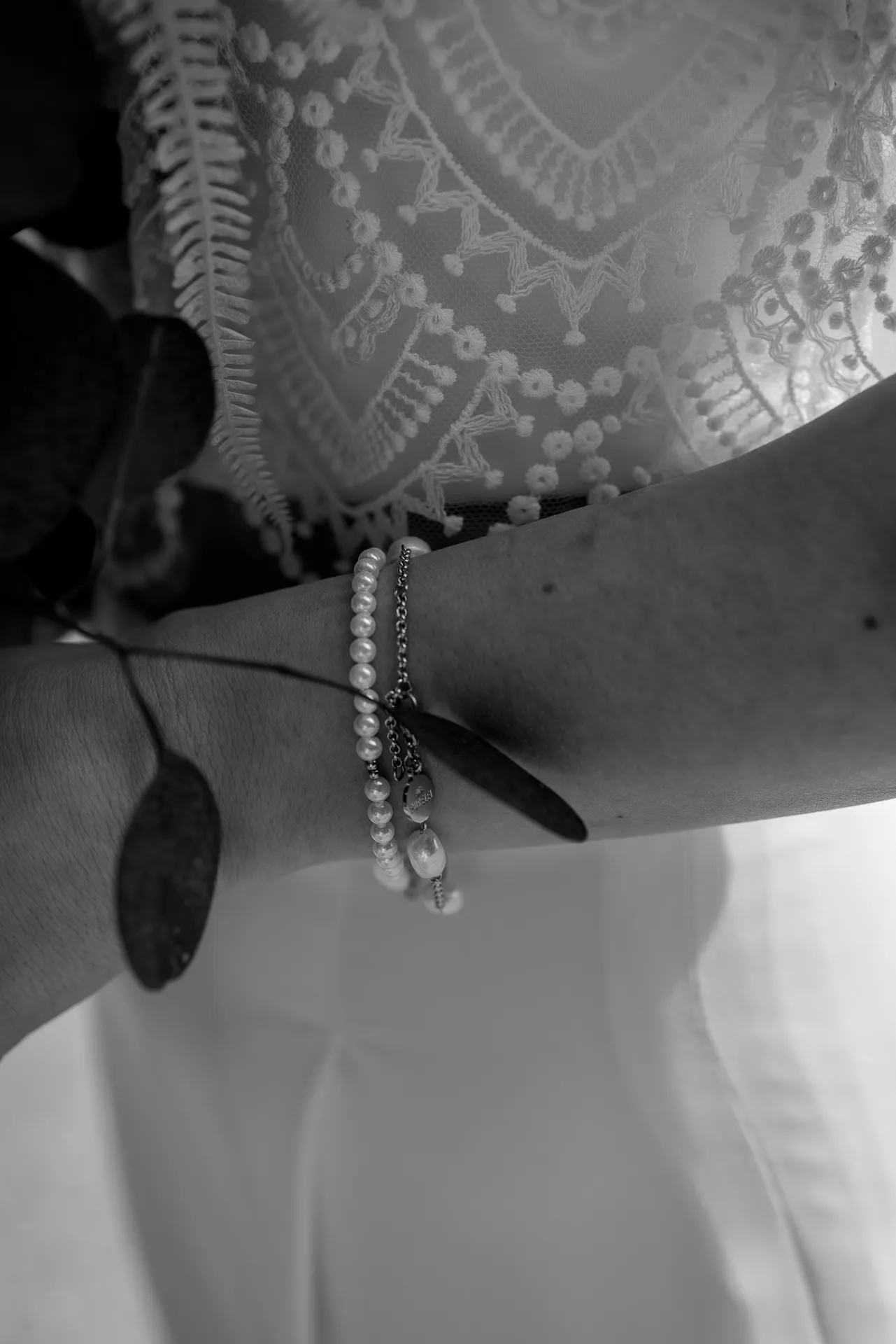 Brautschmuck-Detail mit Perlenarmband und Spitzenkleid in Schwarz-Weiß