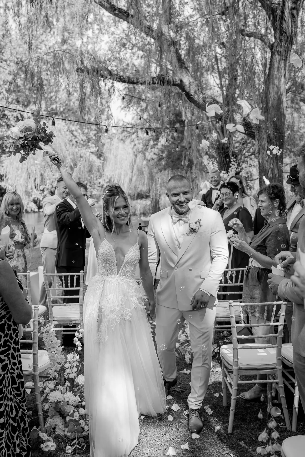 Glücklicher Auszug des Brautpaars nach der Trauung mit Blütenblättern