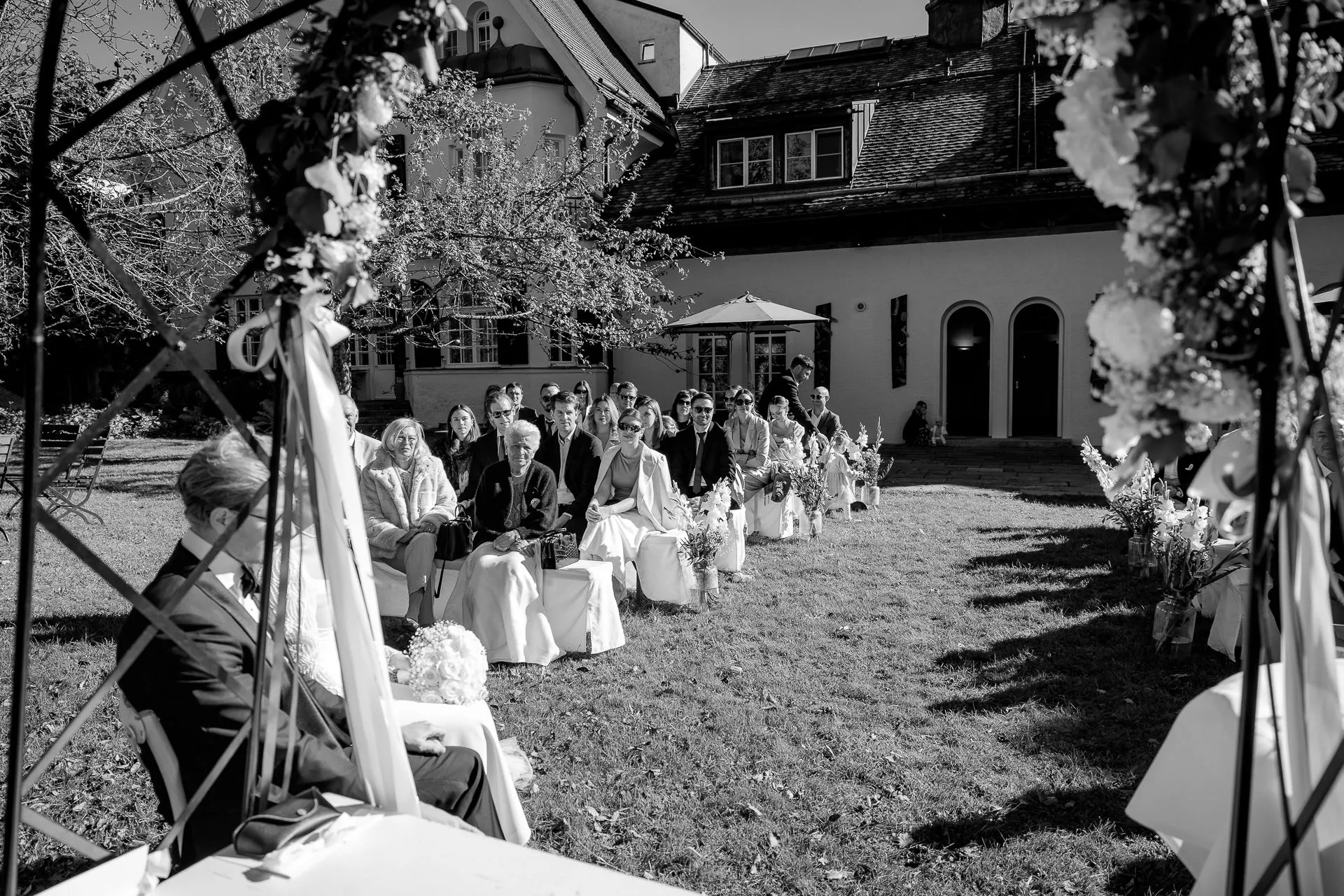 Freie Trauung mit Gästen im Innenhof von Gut Sonnenhausen in Schwarz-Weiß