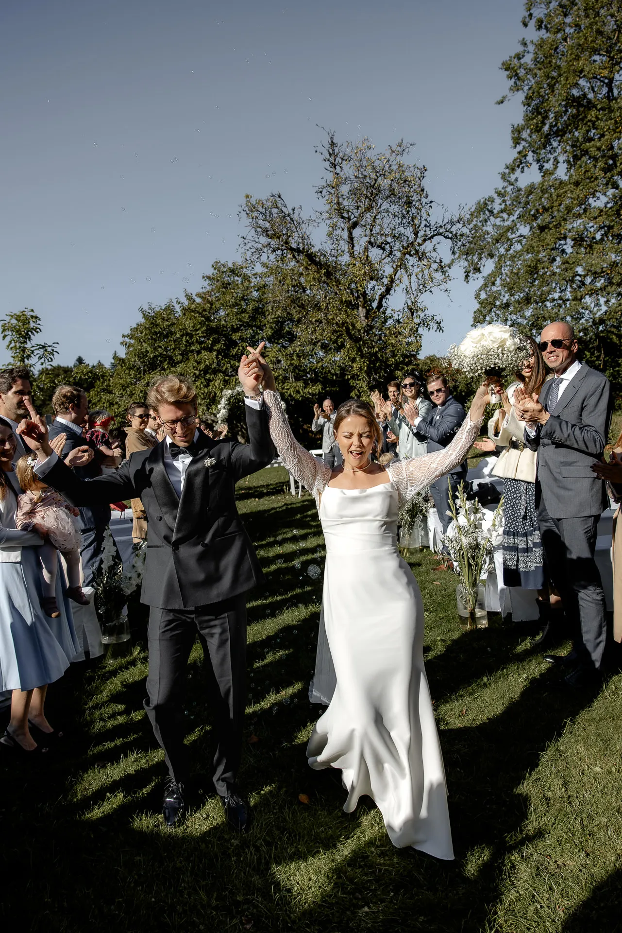 Glückliche Braut jubelt nach Trauung mit Gästen auf Gut Sonnenhausen