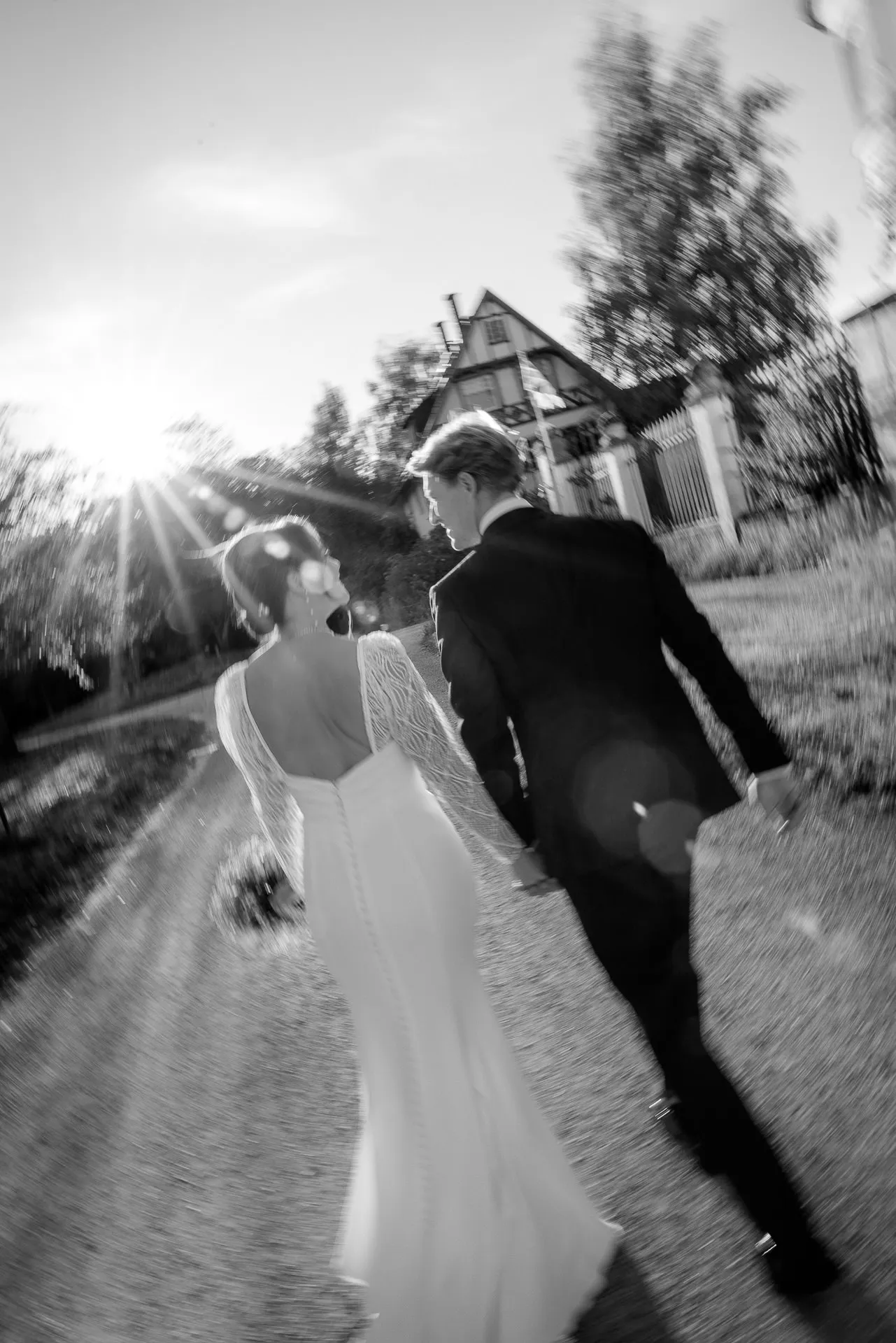 Brautpaar geht Hand in Hand auf Weg bei Hochzeit auf Gut Sonnenhausen in Schwarz-Weiß