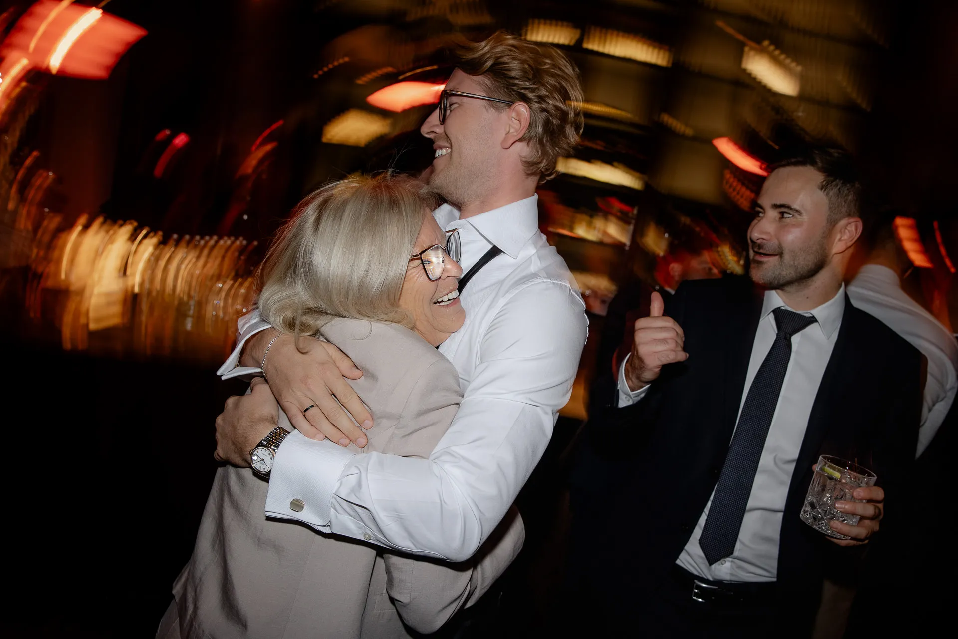 Fröhliche Hochzeitsgäste umarmen sich bei Feier auf Gut Sonnenhausen Hochzeit