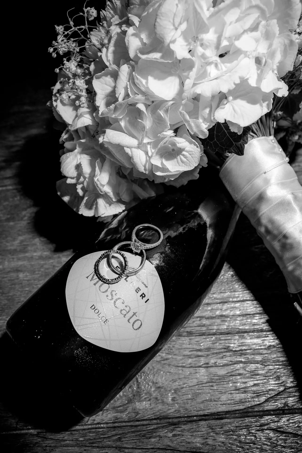 Detailaufnahme Brautstrauß und Eheringe auf Moscato Flasche bei Italien Hochzeit